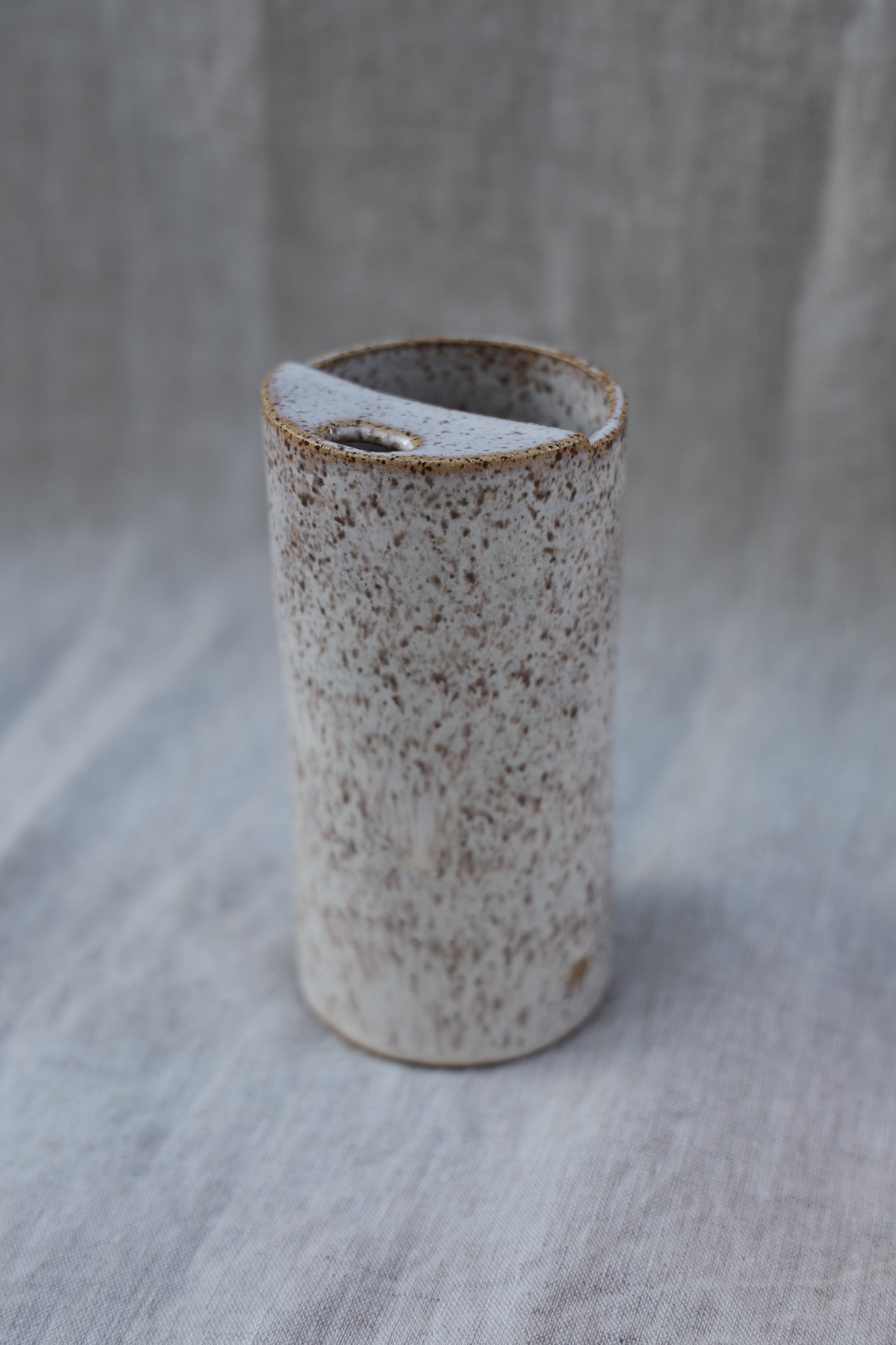Small cylindrical ceramic travel cup with a textured surface on a gray background