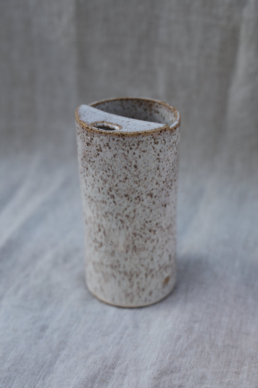 Small cylindrical ceramic travel cup with a textured surface on a gray background