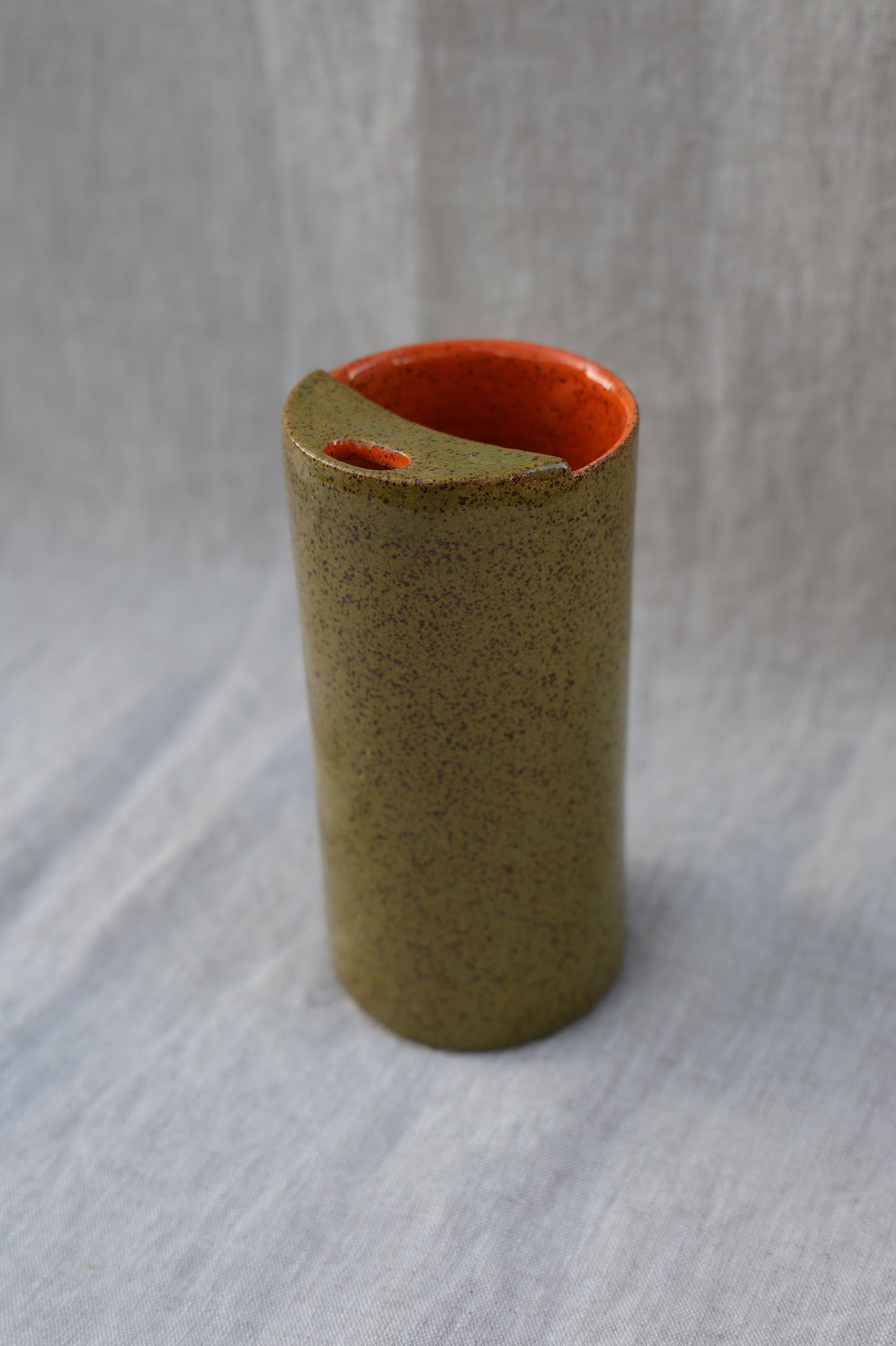 Cylindrical object with red interior on a textured gray background