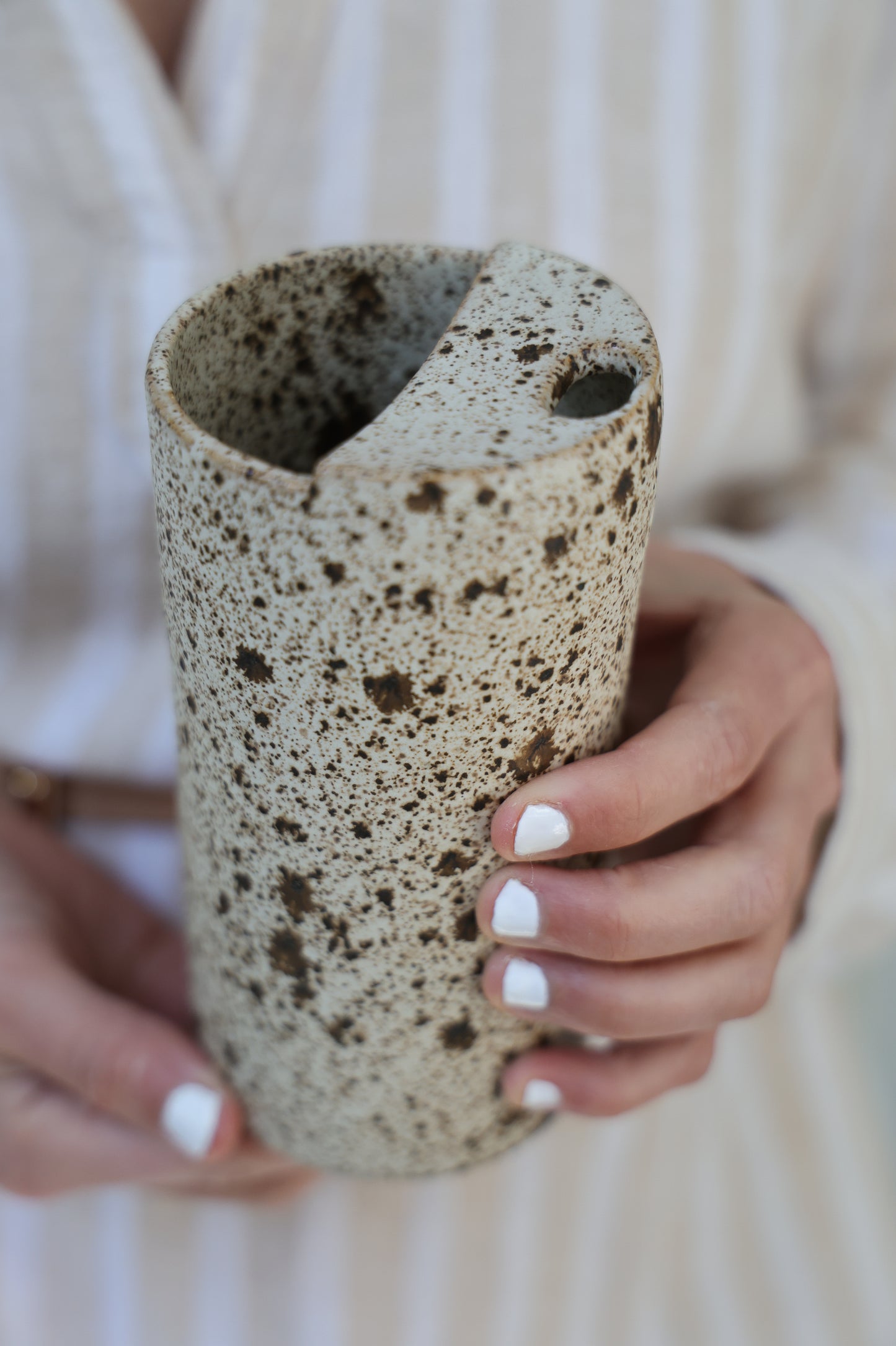 Person holding a textured cylindrical object with a blurred background