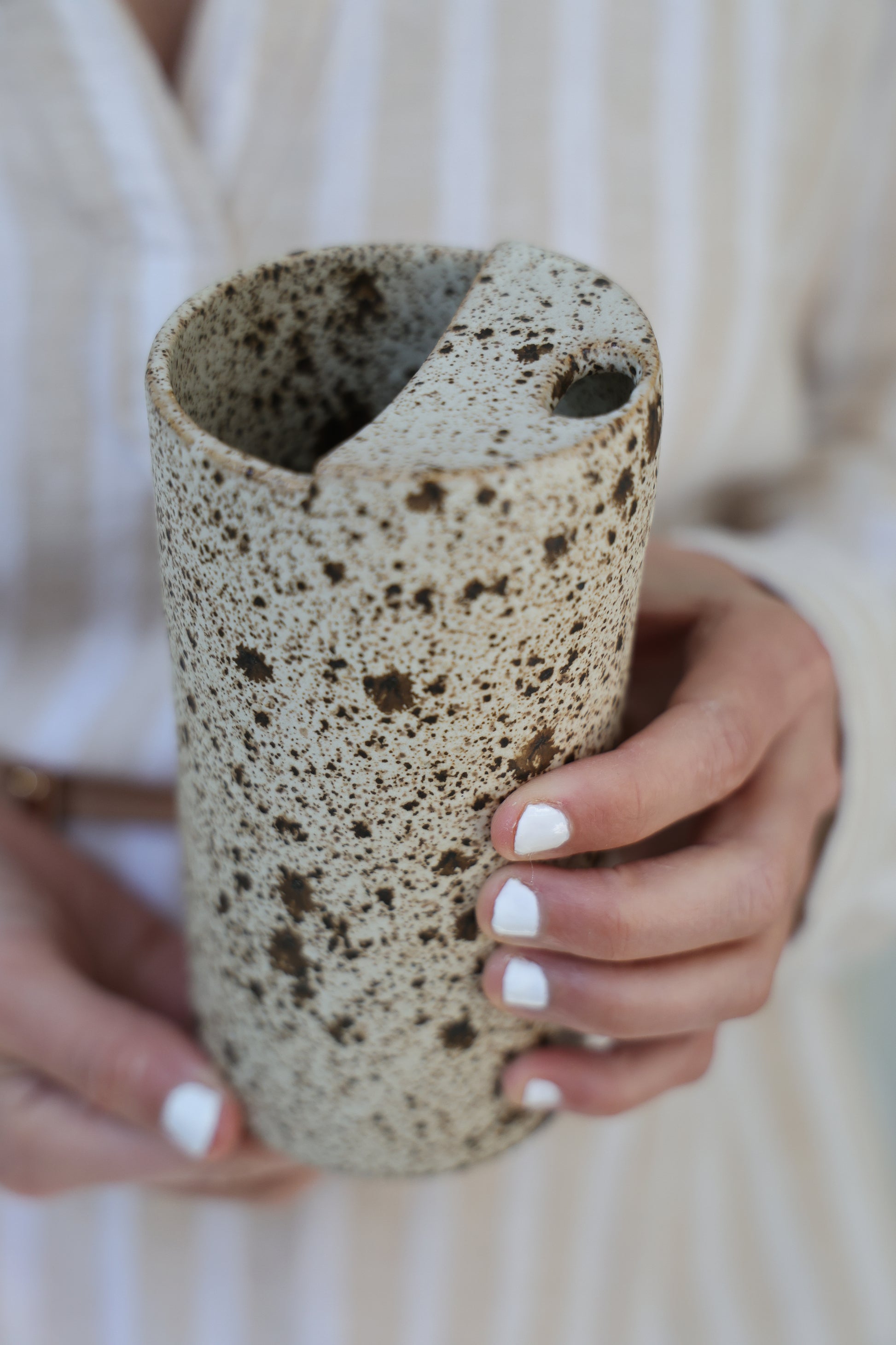 Person holding a textured cylindrical object with a blurred background